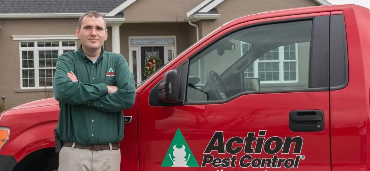 Action Pest Control Technician Standing in Front of Truck