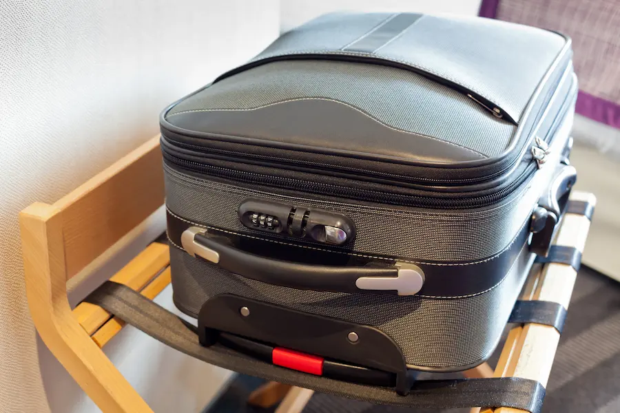 Suitcase sitting on a suitcase rack in a hotel room.