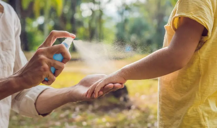Spraying natural mosquito treatment on the arm of a child. There are lots of products to treat mosquito bites, including natural, DIY treatments.