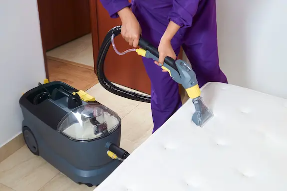 Person steam cleaning a mattress