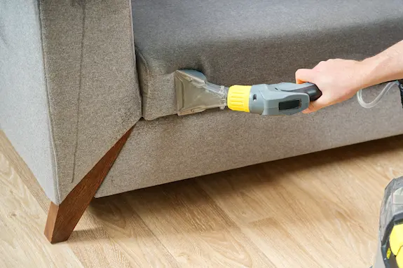 Person steaming cleaning a sofa