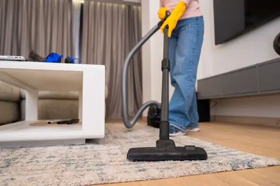 A person vacuuming a rug