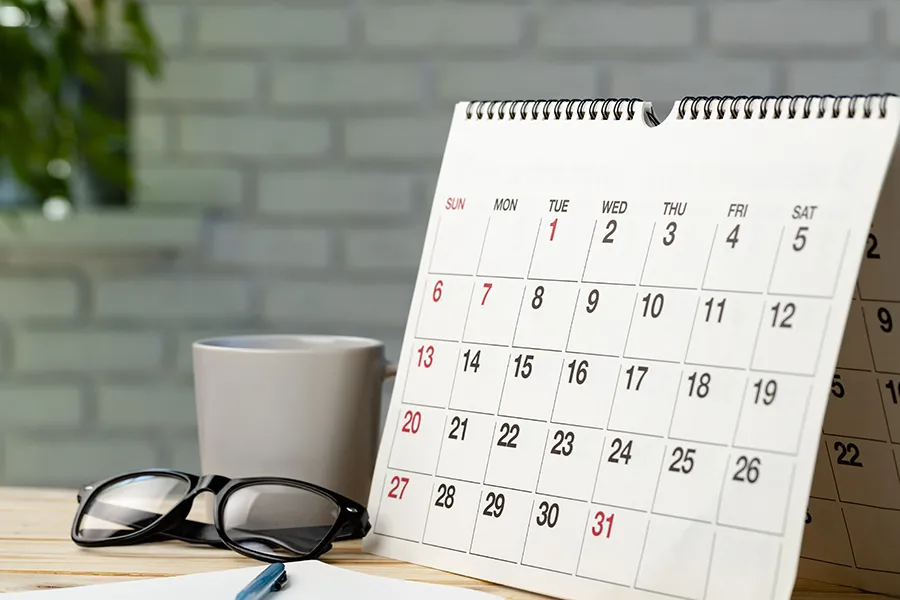 A desktop calendar sitting next to reading glasses, symbolizing the best time to start rodent exclusion planning.